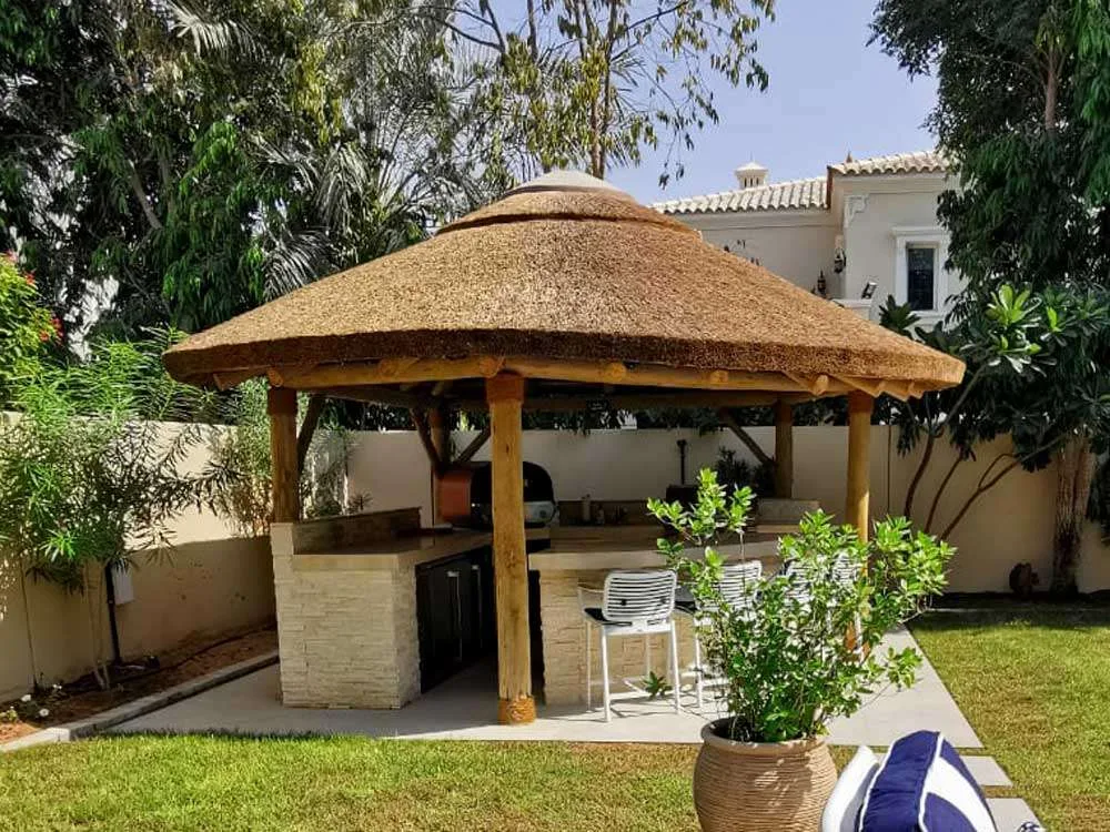 Enjoy the Rustic Charm: Cape Reed Thatched Roof Sheltering a Cozy BBQ Corner